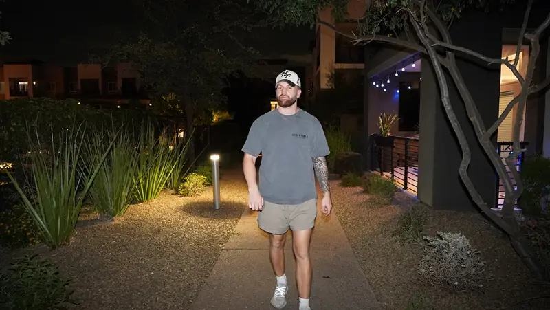 Caleb Hellinger walking a lit desert path in the evening