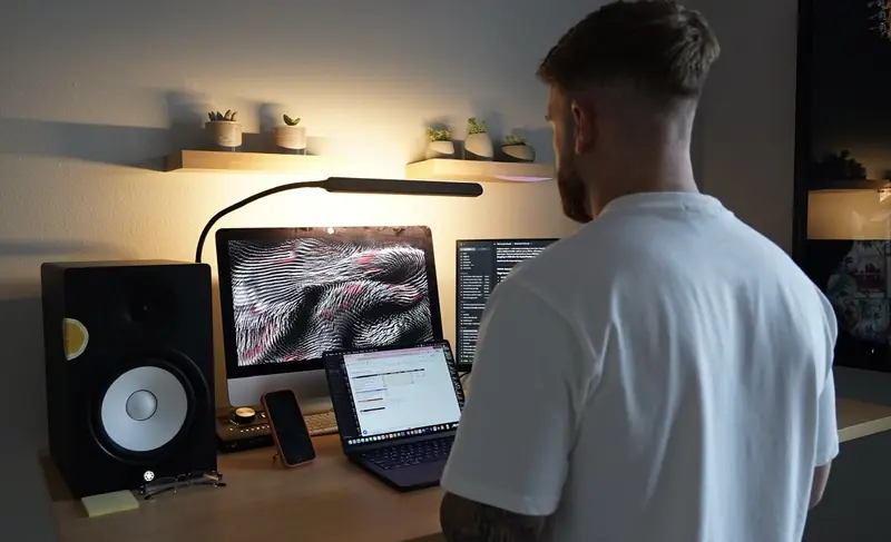 Caleb Hellinger at his desk with studio monitors at night
