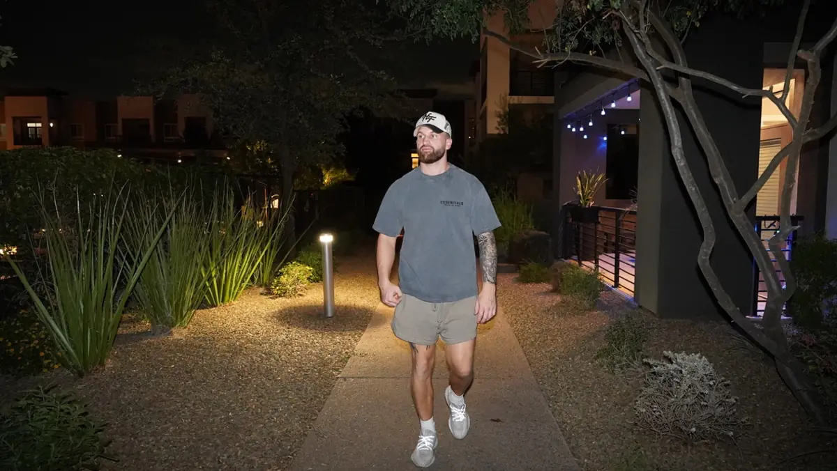 Caleb Hellinger walking a lit path through desert landscaping