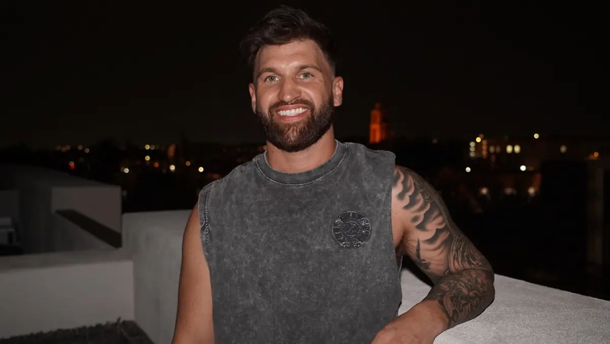 Caleb Hellinger on a rooftop at night above city lights