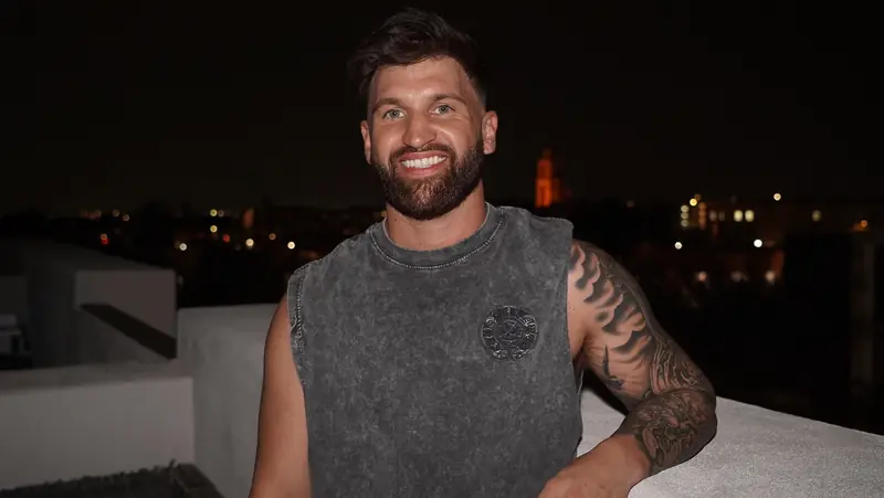 Caleb Hellinger on a rooftop at night above city lights