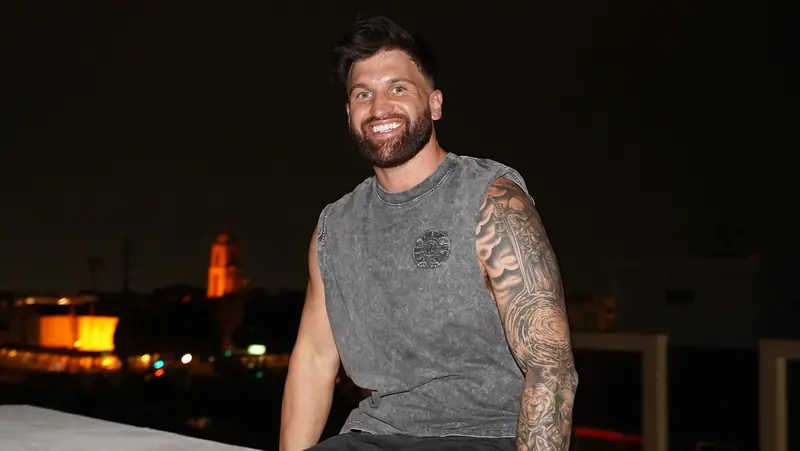 Caleb Hellinger smiling on a rooftop above the skyline