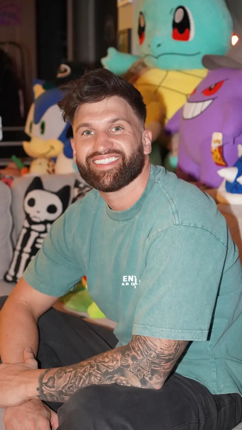 Caleb Hellinger seated at home in a teal tee