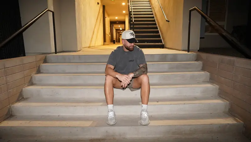 Caleb Hellinger seated on outdoor stairs at night, wide