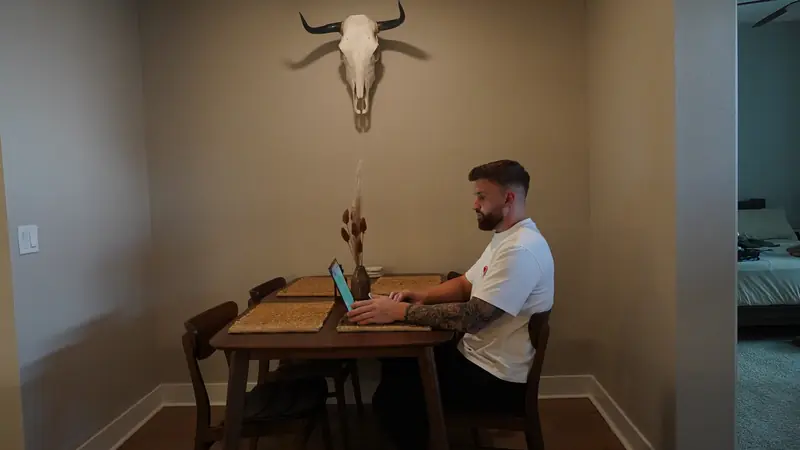 Caleb Hellinger working on a laptop at a dining table